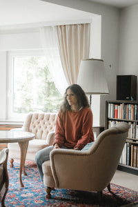 Sophie Mutlu sitting in a quiet vintage living room, surrounded by books and soft light, reflecting during her time alone in Germany.