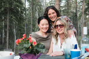 Three close friends gathered around a picnic table, sunlight filtering through the trees, laughter in the air.