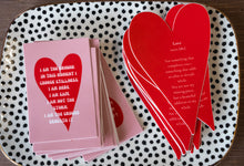 Stack of pink heart-shaped affirmation stickers reading “I am the ground” displayed on a dotted ceramic tray.